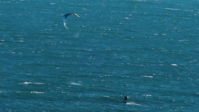 Distant view of a man kitesurfing on a sunny day