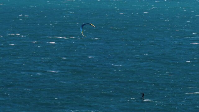 Distant view of a man kitesurfing on a sunny day