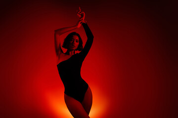 Stylish woman posing in silhouette with vibrant gradient orange and red light on background