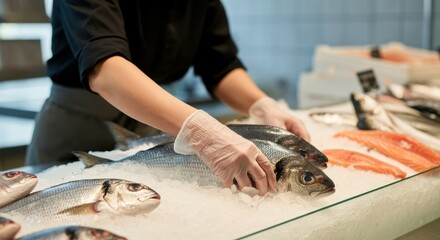 Female worker arranging fresh fish on ice at seafood market counter