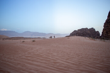 a man rides a camel in the desert,a hot place,the ecology is clean,fine desert sand,camels that carry people and do not suffer from thirst,the hot sun burns the sands,no water,no plants
