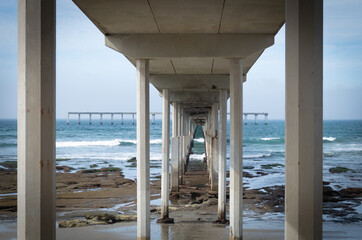 An abstract architectural view of squares and lines from underneath a giant concrete pier on the...