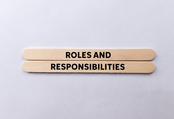 Roles and responsibilities message written on wooden sticks on white background. Conceptual roles...