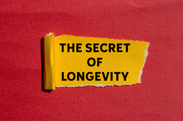 The secret of longevity message written on ripped torn yellow paper on red background. Conceptual the secret of longevity symbol. Copy space.
