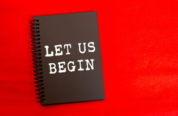 Let us begin message written on black notebook page on red background. Conceptual let us begin symbol. Copy space.