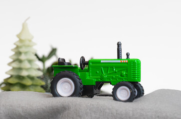 whimsical green toy tractor model on setting with green trees