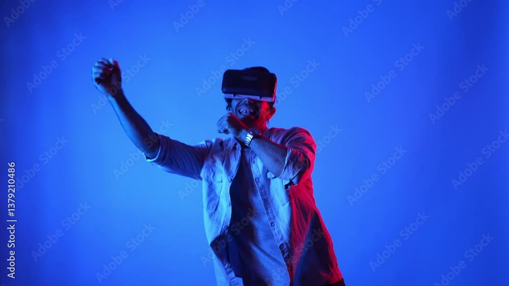 Poster happy dancer dancing and singing to song while wearing vr glasses at blue background. attractive man