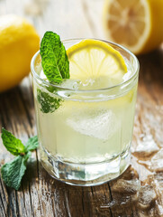 Fototapeta premium Refreshing lemonade with ice and mint on rustic wooden table