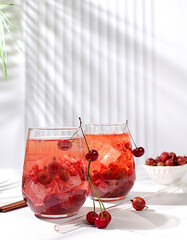 Cold homemade lemonade cocktail, mojito with mint, cherry and gooseberry on a sunny table,...
