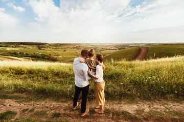 Happy Childhood. Rear view portrait of family of three standing in the middle of the field and enjoying landscape