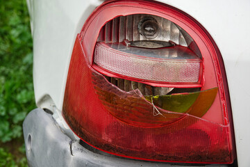 A close-up view shows a damaged car taillight with cracked glass and exposed plastic.