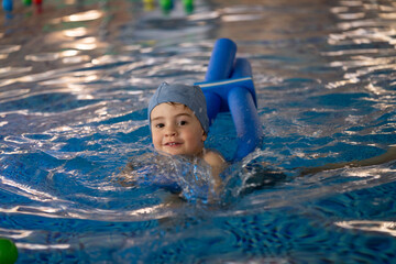 Child swimming with floatation device in indoor pool