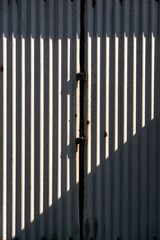 Metalowa ściana z rdzawymi przetarciami i pionowymi cieniami industrialny klimat