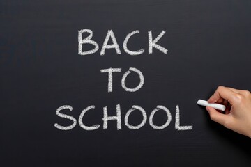 Fototapeta premium Back to school - female hand writing text with chalk on chalkboard or blackboard.