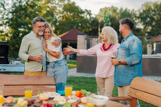 Happy families embracing and greeting at a backyard barbecue party - Powered by Adobe