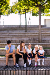 Fototapeta premium Children of different ages in school uniforms sitting on the steps outside