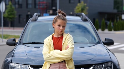Camera moving to beautiful young teen girl standing in front of car on street looking at camera....