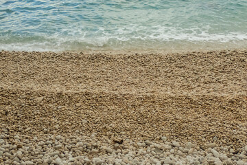 Pebble beach with gentle turquoise waves washing ashore, creating a serene coastal scene with natural textures and soothing colors—perfect for themes of summer, relaxation, and travel