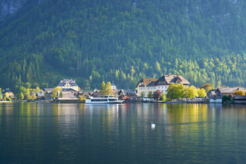 Fototapeta premium Tour Boat at Dock Hallstatt Austria. A tourist passenger boat docks in beautiful Hallstatt, Austria as a swan glides by.