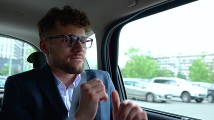 heerful young man having fun while listening the music during riding at the back seat in the tax...