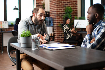 Caucasian man seated at desk, describing his work experiences to african american recruiter. Black...