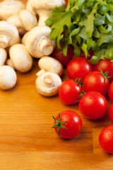 Tomatoes, mushrooms and rocket salad on wooden table, focus on foreground