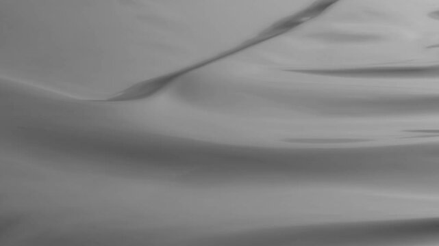 Luxurious gray fabric gracefully flowing and rippling, showcasing dynamic texture with soft, fluid movement against subtle light and shadow