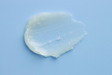 Moisturizing lip balm on light blue background, top view