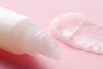 Tube with moisturizing lip balm on pink background, closeup