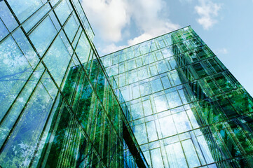 Modern building and lush trees against blue sky, double exposure. Low angle view