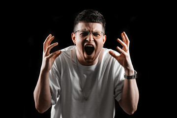 Angry young man screaming with furious facial expression. Hands raised in frustration. Emotional...