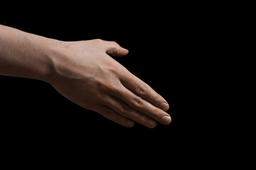 Close-up of human hand reaching out for handshake on black background. Concept of greeting,...