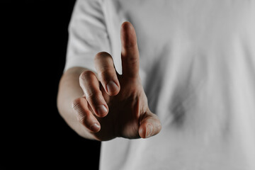 Obraz premium Close-up of human hand pointing with index finger on black background. Gesture of direction, touch or attention. Concept of choice, decision, interaction, touchscreen or communication.