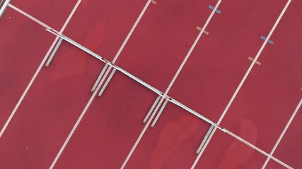 Aerial top view of a solo male athlete sprinting along a marked track lane, showcasing the track boundaries, emphasizing speed, focus, and precision in motion. Cinematic drone slow motion