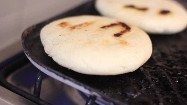 Turning the corn cake or arepa over the hot surface of the cast iron pan or budare.