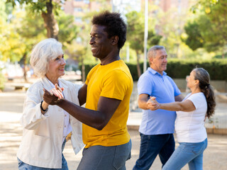 Happy cheerful positive smiling adult friends dancing pair dance in garden