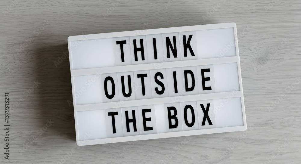 Poster illuminated light box displaying think outside the box quote on tabletop