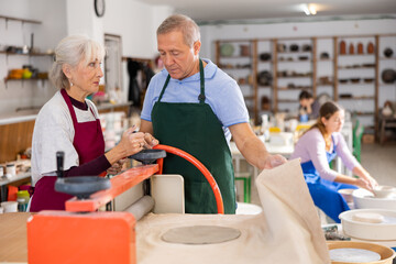 Fototapeta premium elderly potter passes on experience of hand-making products from fresh clay