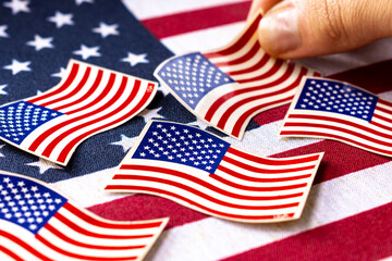Obraz premium Hand taking American flag-themed stickers. Represents the essence of democracy, politics national pride and unit.
