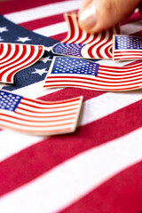 Vertical shot of hand taking American flag-themed stickers. Represents the essence of democracy, politics national pride and unit.