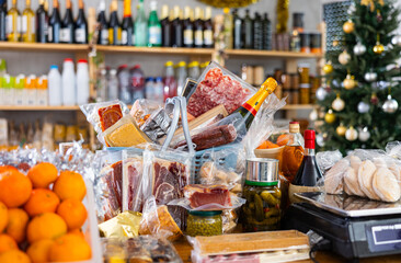 Various products on a store counter - dried meat, canned green peas, canned cucumbers, smoked sausage, fruit, champagne, alcohol and many other foods