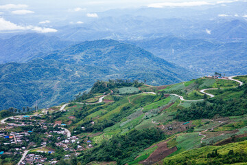Fototapeta premium Scenic mountain road curves through lush green hills aerial view nature landscape in countryside environment