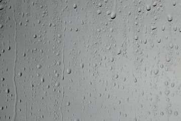 Water drops on grey glass surface, closeup