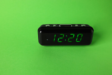 Digital alarm clock showing 12:20 o'clock on green background, space for text
