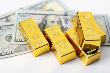 Shiny gold bars and dollar banknotes on white background, closeup