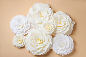 Beautiful white paper flowers on beige background, flat lay