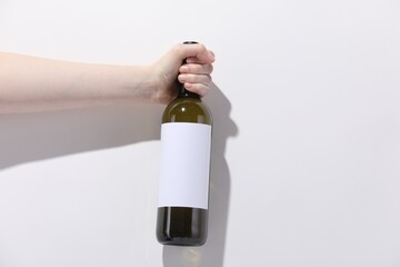 Woman with bottle of wine on white background, closeup. Space for text