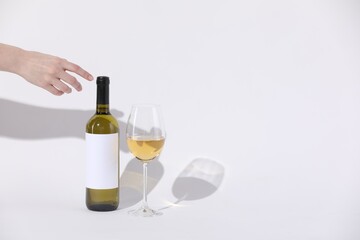 Woman with bottle of wine and glass on white background, closeup. Space for text