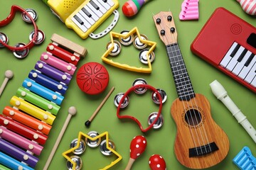 Different toy musical instruments on green background, flat lay
