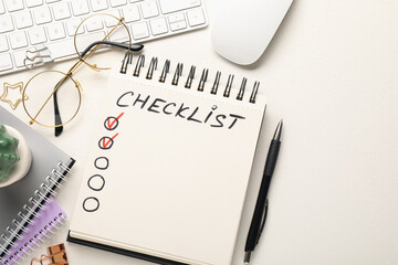 Checklist with marked checkboxes, different stationery, glasses, computer keyboard and mouse on white table, flat lay. Space for text